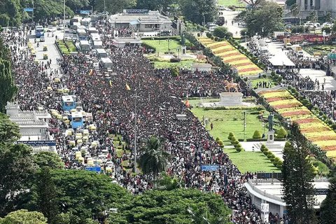 Para penggemar berdiri di antara sepatu terbengkalai dan penghalang yang runtuh setelah insiden berdesakan di luar Stadion M. Chinnaswamy di Bengaluru pada 4 Juni 2025. (AFP)