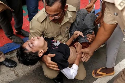 Para penggemar berdiri di antara sepatu terbengkalai dan penghalang yang runtuh setelah insiden berdesakan di luar Stadion M. Chinnaswamy di Bengaluru pada 4 Juni 2025. (AFP)