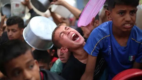 Anak-anak Palestina berkumpul untuk menerima makanan yang dimasak di sebuah titik distribusi di Nuseirat, Jalur Gaza Tengah, pada 11 Juni 2025. (Eyad BABA/AFP)