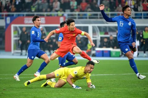 Aksi bintang Timnas China, Wu Lei (merah) saat menghadapi hadangan dari kiper Timnas Singapura, Hassan Sunny di putaran kedua Kualifikasi Piala Dunia 2026. (AFP).