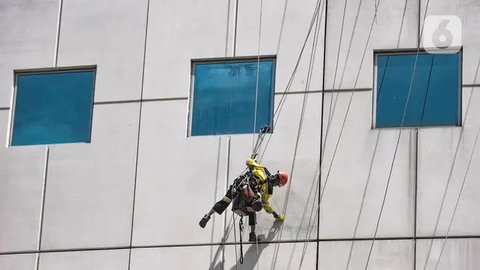 Seorang pekerja melakukan perawatan gedung perkantoran di kawasan Sudirman, Jakarta, Senin (30/11/2020). Menaker Ida Fauziyah menyatakan BSU BLT BPJS Ketenagakerjaan termin 2 tahap 6 senilai