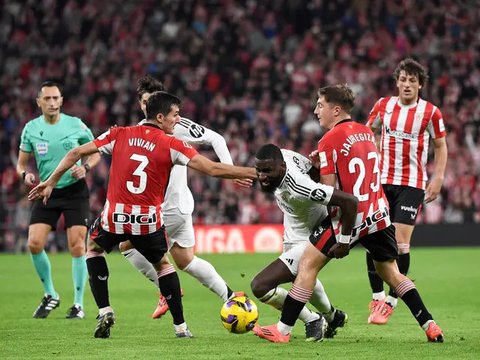 Pemain Real Madrid, Jude Bellingham berebut bola dengan pemain Athletic Bilbao, Mikel Jauregizar (kanan) dan Yeray Alvarez (kiri) pada laga lanjutan Liga Spanyol 2024/2025 di San Mames Stadiu