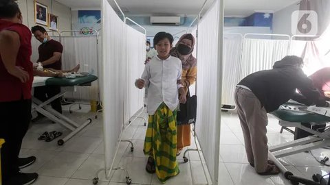Seorang anak didampingi orang tuanya usai mengikuti sunatan massal yang diselenggarakan oleh Pemerintah Provinsi DKI Jakarta di RSUD Kebayoran Baru, Kamis (26/6/2025). (Liputan6.com/Herman Zakharia)