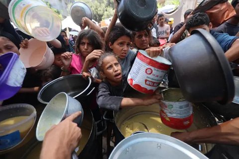 Anak-anak Palestina mengantre untuk menerima makanan hangat di sebuah titik distribusi makanan di Nuseirat pada 30 Juni 2025. (Eyad BABA/AFP)