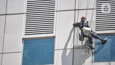 Seorang pekerja melakukan perawatan gedung perkantoran di kawasan Sudirman, Jakarta, Senin (30/11/2020). Menaker Ida Fauziyah menyatakan BSU BLT BPJS Ketenagakerjaan termin 2 tahap 6 senilai