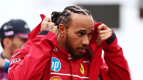 Pembalap Ferrari,  Lewis Hamilton, melambaikan tangan ke fans saat parade pembalap sebelum balapan F1 GP Inggris di Sirkuit Silverstone, Minggu (6/7/2025). (AFP/Ben Stansal)