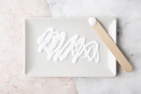 Kamar mandi minimalis dengan kloset duduk, shower berdinding kaca, wastafel gantung, dan keramik abu-putih berpola kotak kecil. (Liputan6.com/MetaAI)