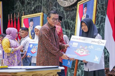 Orangtua dari anak penerima saat menunjukkan KJP yang baru diterima di kawasan Matraman, Jakarta, Selasa (24/11/2020). Penyaluran KJP plus tahap kedua ini menggunakan data baru berdasarkan pe