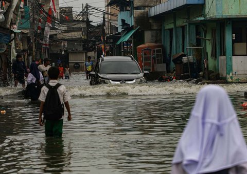 Sebuah mobil menerobos banjir rob yang merendam kawasan Muara Baru, Jakarta Utara, Selasa (14/1/2025).