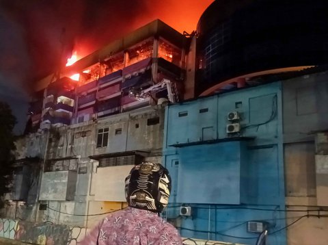 Warga melihat kebakaran yang melahap bangunan Glodok Plaza, Jakarta, Rabu (15/1/2025) malam.