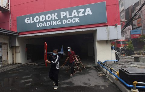 Pekerja mengeluarkan barang-barang dari Glodok Plaza yang terbakar hebat, pada Kamis (16/1/2025).