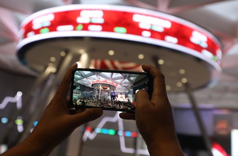 Pengunjung memotret suasana pembukaan perdagangan perdana Bursa Efak Indonesia 2025 di Mainhall Gedung BEI di Jakarta, Kamis (2/1/2025).
