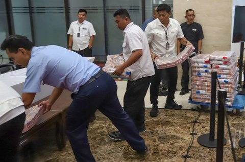 Petugas bersiap menampilkan tumpukan uang senilai Rp61 miliar yang menjadi barang bukti kasus judi online dalam konferensi pers di Mabes Polri, Jakarta, Senin (20/1/2025).