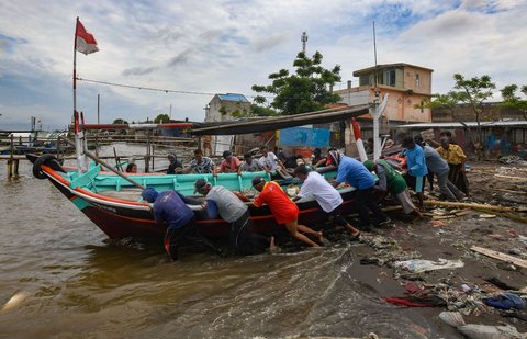 Warga bergotong-royong membawa perahu nelayan, yang telah direkondisi, kembali ke lautan di Kampung Nelayan Tanjung Pasir, Tangerang, Banten, Rabu (22/1/2025).