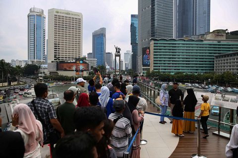 Warga mengantre untuk berfoto di Anjungan Halte Transjakarta Bundaran HI Astra, Jakarta, selama libur peringatan Isra Mikraj, Senin (27/1/2025).