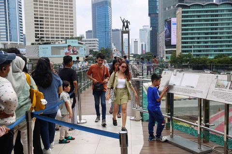 Warga mengantre untuk berfoto di Anjungan Halte Transjakarta Bundaran HI Astra, Jakarta, selama libur peringatan Isra Mikraj, Senin (27/1/2025).
