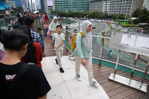Warga seusai berfoto di Anjungan Halte Transjakarta Bundaran HI Astra, Jakarta, selama libur peringatan Isra Mikraj, Senin (27/1/2025).