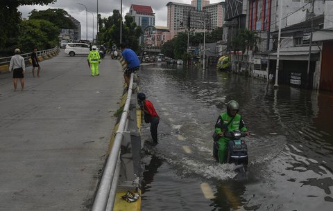 Pengemudi ojek online nekat melewati banjir yang merendam ruas Jalan Satria, Grogol, Jakarta Barat, Rabu (29/1/2025).