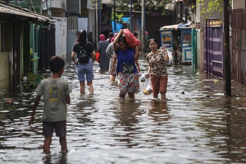 Warga melintasi banjir setinggi lutut orang dewasa yang merendam pemukiman penduduk di kawasan Cengkareng Barat, Jakarta Barat, Kamis (30/1/2025).