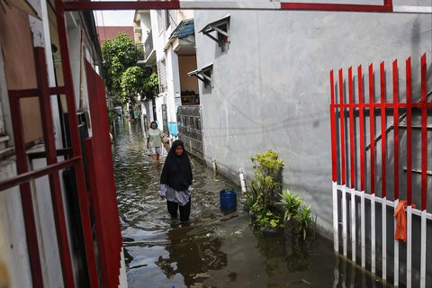 Warga melintasi banjir setinggi lutut orang dewasa yang merendam pemukiman penduduk di kawasan Cengkareng Barat, Jakarta Barat, Kamis (30/1/2025).