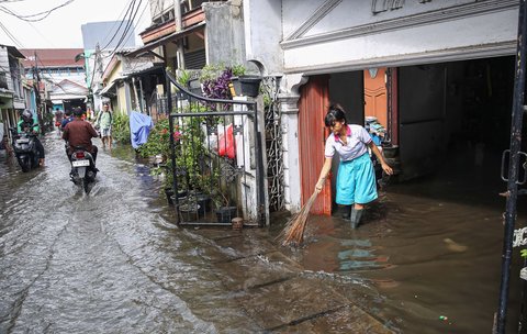 Warga membersihkan rumahnya saat banjir merendam pemukiman penduduk di kawasan Cengkareng Barat, Jakarta Barat, Kamis (30/1/2025).