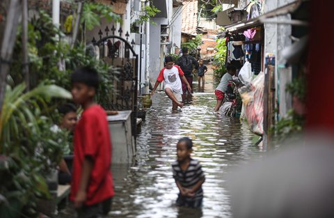 Warga melintasi banjir yang merendam pemukiman penduduk di kawasan Cengkareng Barat, Jakarta Barat, Kamis (30/1/2025).