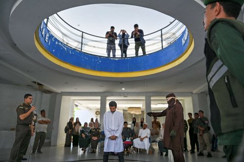 Ekspresi seorang pria tertunduk sambil menahan sakit ketika dicambuk berkali-kali oleh anggota polisi Syariah sebagai hukuman karena terbukti bermain judi online atau maisir di Banda Aceh, Aceh, pada 30 Januari 2025.
