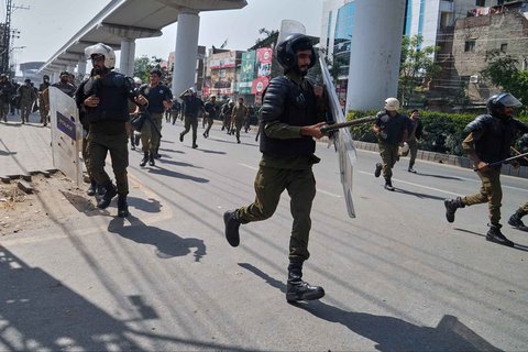 Personel polisi berlarian mencari perlindungan setelah pendukung partai Islam 'Tehreek-e-Labbaik Pakistan' melempari mereka dengan batu dalam bentrokan menjelang pawai pro-Palestina menuju ibu kota Islamabad, di Lahore, Pakistan, Jumat (10/10/2025).