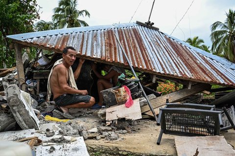 Warga  mencari barang-barang di sebuah rumah yang runtuh di Manay, Provinsi Davao Oriental, Sabtu, (11/10/2025).