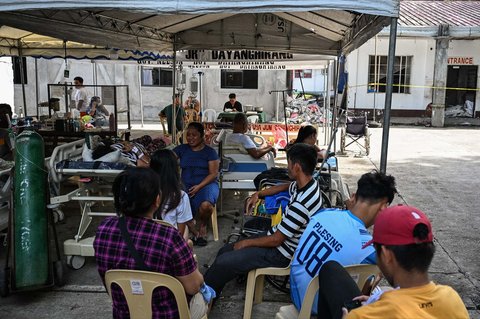 Para pasien menunggu di luar rumah sakit yang rusak di Manay, Provinsi Davao Oriental, Sabtu, (11/10/2025).