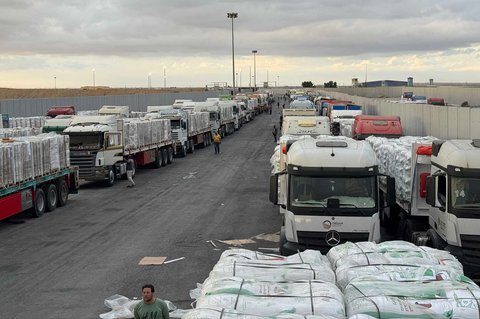 Truk-truk bermuatan bantuan kemanusiaan terparkir menunggu akses ke Jalur Gaza di pertabatasan Mesir, Minggu (12/10/2025).