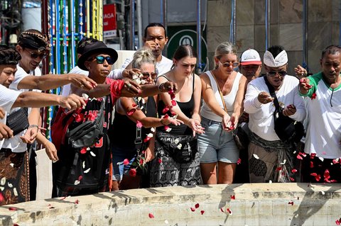 Warga menaburkan bunga  ke tugu peringatan bagi mereka yang gugur dalam peringatan 23 tahun bom Bali 2002 di Kuta,  Bali, Indonesia, Minggu (12/10/2025).
