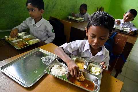 Para siswa menikmati makanan yang disediakan oleh program makanan bergizi gratis di sebuah sekolah dasar di Darul Kamal, Aceh, Senin (13/10/2025).