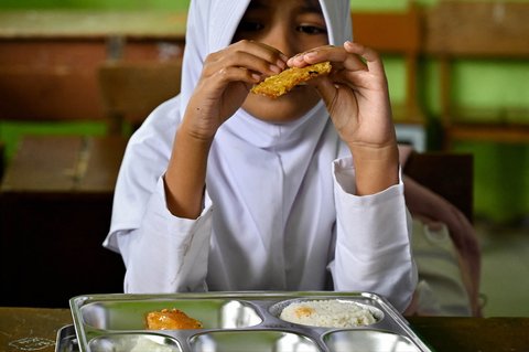 Siswa menikmati makanan yang disediakan oleh program makanan bergizi gratis di sebuah sekolah dasar di Darul Kamal, Aceh, Senin (13/10/2025).