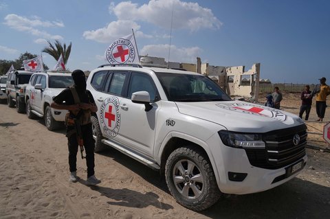 Seorang pria bersenjata Hamas bertopeng berdiri di samping kendaraan Palang Merah yang tiba untuk penyerahan sandera Israel oleh Hamas, di Khan Younis, Jalur Gaza selatan, Senin (13/10/2025).