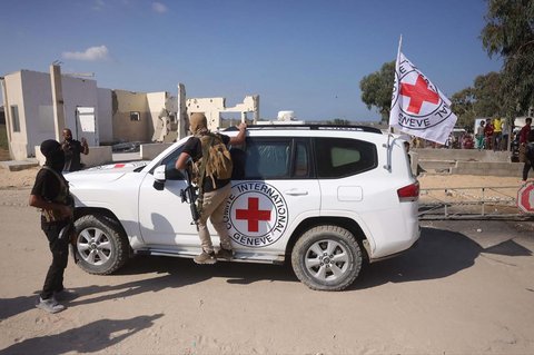 Seorang militan Hamas memimpin mobil Palang Merah Internasional menuju lokasi penyerahan gelombang kedua sandera Israel yang dibebaskan di selatan Deir al-Balah di Jalur Gaza tengah, Senin (13/10/2025).