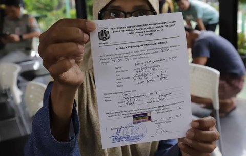 Warga menunjukkan surat bebas rabies  di Ruang Publik Terpadu Ramah Anak (RPTRA) Manggarai, Jakarta, Senin (14/10/2025)
