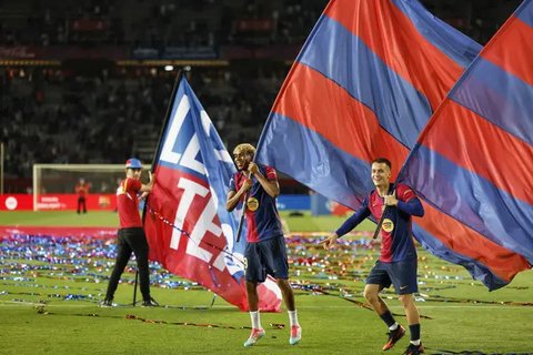 Lamine Yamal (tengah) dan Marc Casado (kanan) dari Barcelona dalam selebrasi juara La Liga setelah pertandingan antara Barcelona dan Villarreal di Estadi Olympic Lluis Companys, Minggu, 18 Mei 2025. (AP Photo/Joan Monfort)