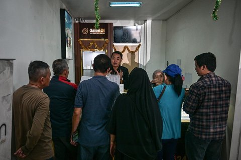 Pelanggan berbincang dengan penjual di Galeri 24, peritel emas milik negara, di Surabaya, Jawa Timur, Kamis (16/10/2025).