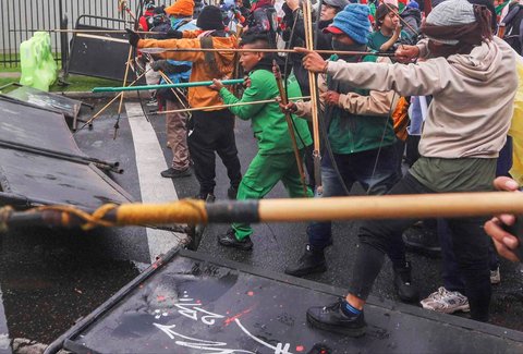 Para demonstran  menembakkan panah ke arah petugas polisi di dekat pintu masuk Kedutaan Besar AS di Bogota, Kolombia, Jumat (17/10/2025) waktu setempat.