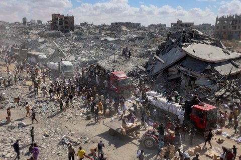 Warga Palestina berebut bahan  makanan pada truk bantuan yang masuk dari perlintasan Karem Abu Salem, di Khan Yunis, Jalur Gaza selatan, Minggu (12/10/2025).