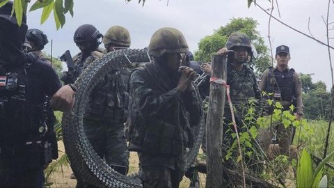 Petugas kepolisian Kamboja berjaga di depan gerbang yang ditutup di pos pemeriksaan perbatasan internasional Poipet, yang menghubungkan Kamboja dan Thailand, di Provinsi Banteay Meanchey,