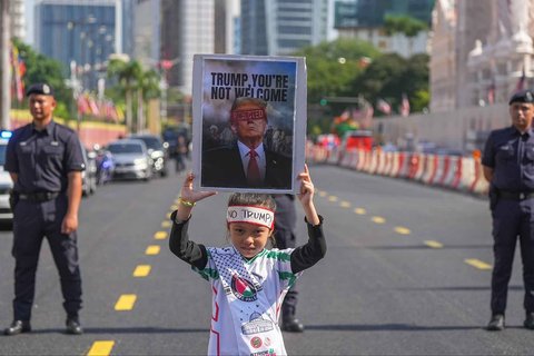 Seorang anak memegang poster saat demonstrasi menentang kehadiran Presiden AS Donald Trump di KTT ASEAN di Kuala Lumpur, Malaysia, Minggu (26/20/2025).