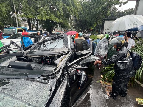 Sebuah mobil mewah Lexus tertimpa pohon tumbang di Jalan Metro Pondok Indah, Jakarta, Minggu (26/10/2025).