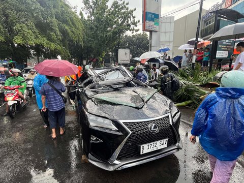 Sebuah mobil mewah Lexus tertimpa pohon tumbang di Jalan Metro Pondok Indah, Jakarta, Minggu (26/10/2025).