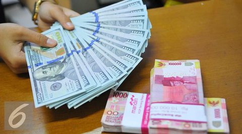 Karyawan menunjukkan uang dolar AS dan rupiah di Jakarta, Rabu (30/12/2020). Nilai tukar rupiah di pasar spot ditutup menguat 80 poin atau 0,57 persen ke level Rp 14.050 per dolar AS. (Liputa