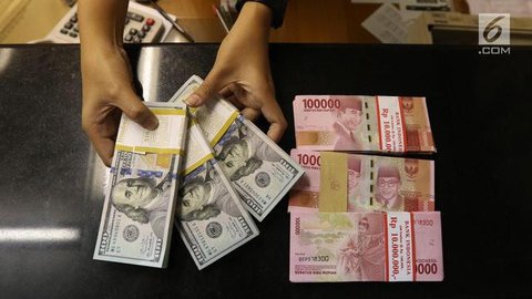 Karyawan menunjukkan uang dolar AS dan rupiah di Jakarta, Rabu (30/12/2020). Nilai tukar rupiah di pasar spot ditutup menguat 80 poin atau 0,57 persen ke level Rp 14.050 per dolar AS. (Liputa