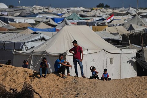 Anak-anak menyaksikan saat bekho dan dan pekerja  asal Mesir mencari jenazah para sandera di dekat kamp tenda pengungsi Palestina di Kota Hamad, Khan Younis, di Jalur Gaza selatan, Selasa, (28/10/2025).