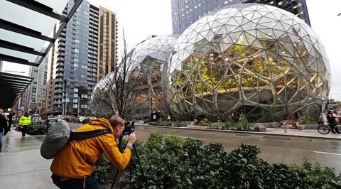 Pejalan kaki melewati The Spheres, kantor bernuansa hutan hujan yang baru dibuka Amazon, di Seattle, AS, Senin (29/1). The Spheres terdiri dari tiga rumah kaca berukuran bulat yang menaungi 4