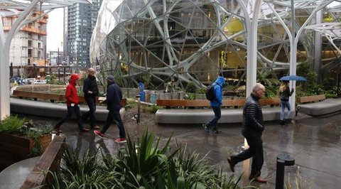 Pejalan kaki melewati The Spheres, kantor bernuansa hutan hujan yang baru dibuka Amazon, di Seattle, AS, Senin (29/1). The Spheres terdiri dari tiga rumah kaca berukuran bulat yang menaungi 4